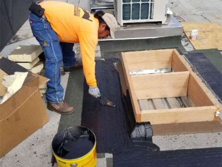 A McDonald & Wetle employee performs roof repairs on a commercial building